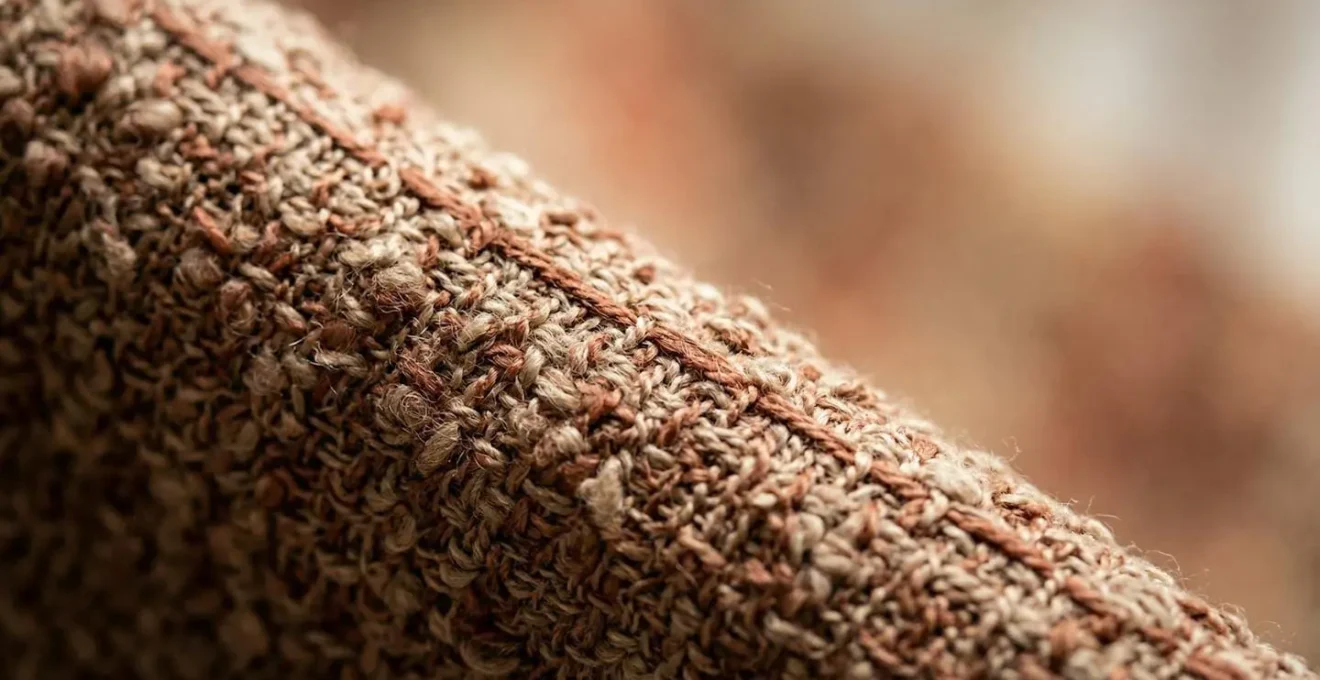 Dettaglio ravvicinato di tessuto per tende in tonalità terracotta desaturata con texture bouclé